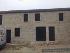 Pose de menuiseries en aluminium noir avec volets roulants monobloc.