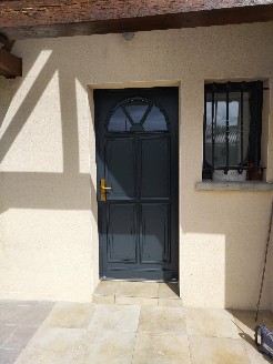 Pose d'une porte d'entrée en bois exotique gris extérieur et blanc intérieur.